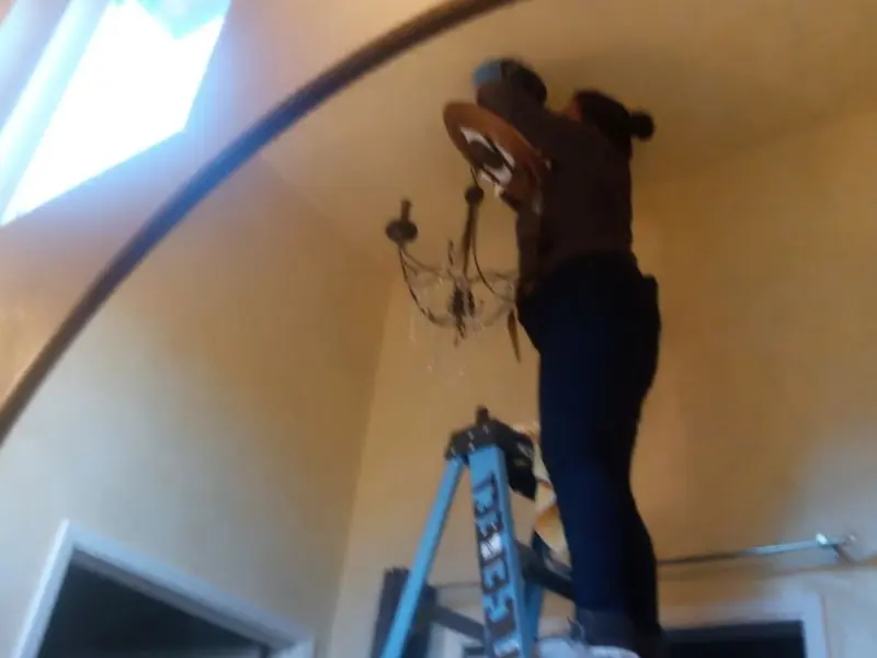 Electrician installing a chandelier in a Everman residence